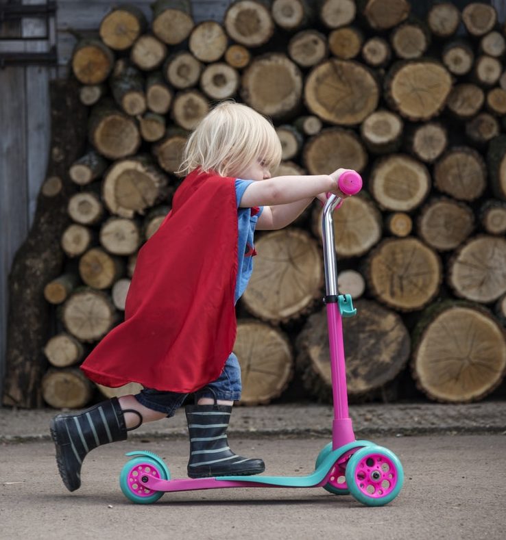 girl riding scooter with cape