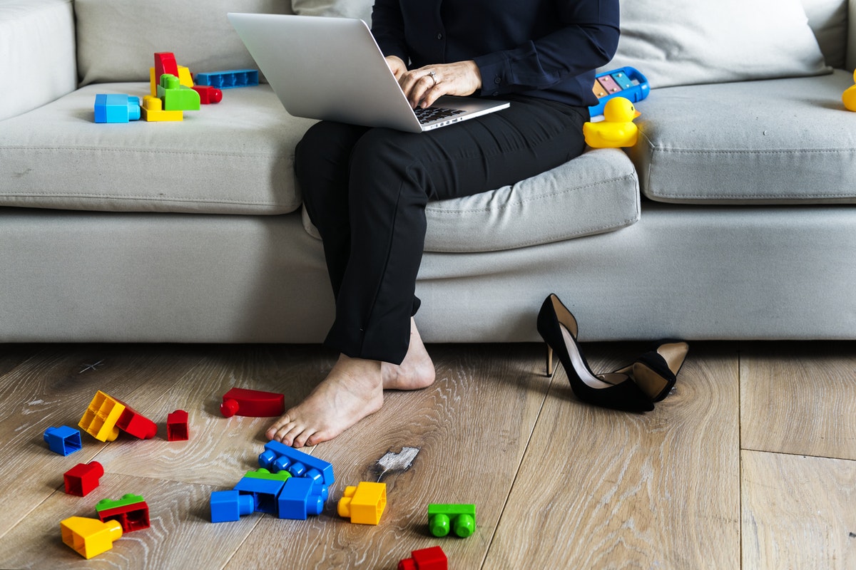 mom working on couch with legos on floor